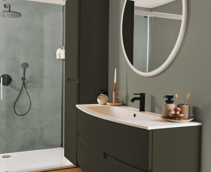 Meuble de salle de bain vert avec tiroir incurvé. Robinet de lavabo noir et miroir rond