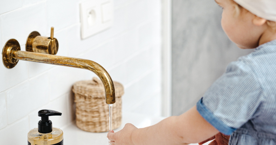 Un enfant se lave les mains sous un robinet