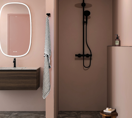 Tendance salle de bain avec murs rose blush, sanitaires noirs, sol en marbre et meuble de salle de bain moderne en bois avec miroir éclairé.