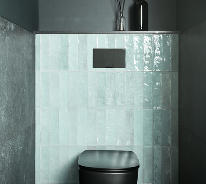 Toilet moderne avec cuvette noire, carrelage vert sur le mur arrière et murs foncés pour un contraste élégant.