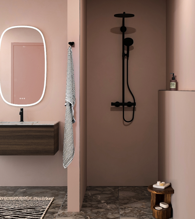 Tendance salle de bain avec murs rose blush, sanitaires noirs, sol en marbre et meuble de salle de bain moderne en bois avec miroir éclairé.