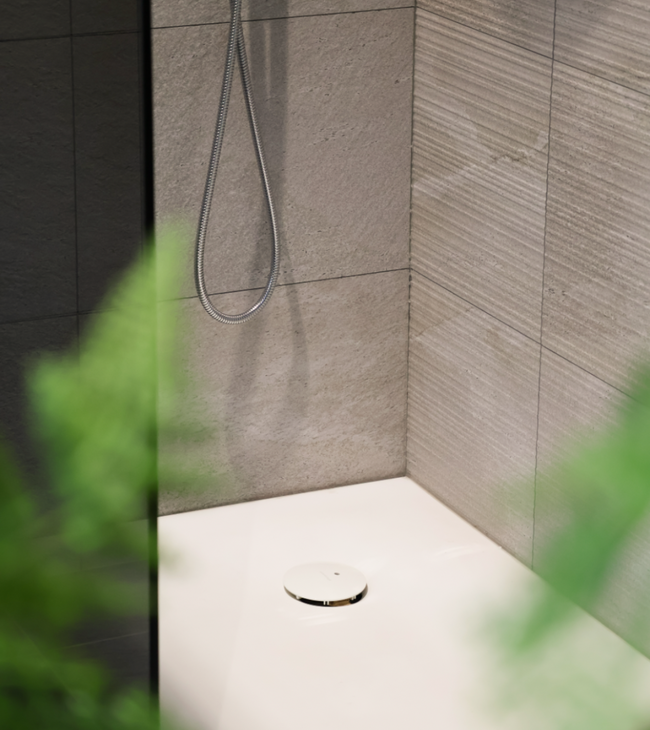 Douche de style biophilique avec bac à douche blanc mat, carreaux muraux naturels et plantes vertes pour une ambiance apaisante.