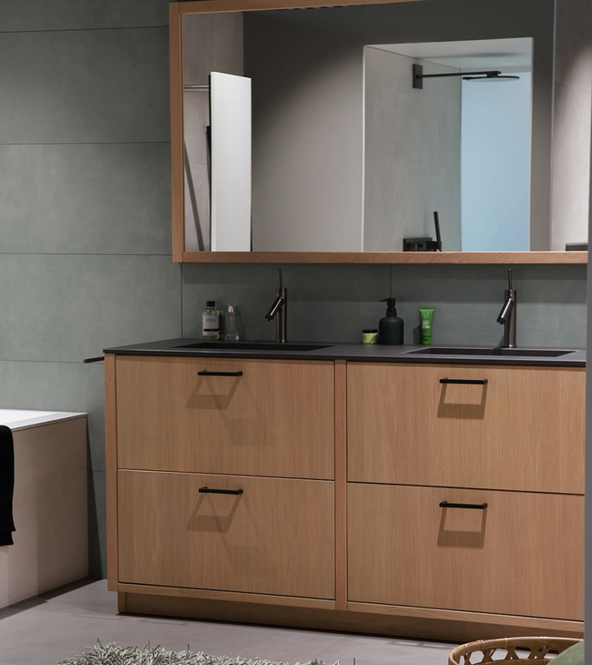 Salle de bain avec grande miroir au-dessus d’un meuble double vasque dans un style biophilique, entourée de matériaux et de tons naturels.