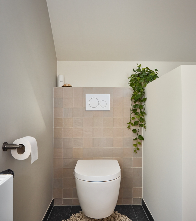 Toilettes aux finitions épurées avec carrelage mural beige et WC suspendu moderne, faisant partie d’une rénovation complète de la salle de bain.