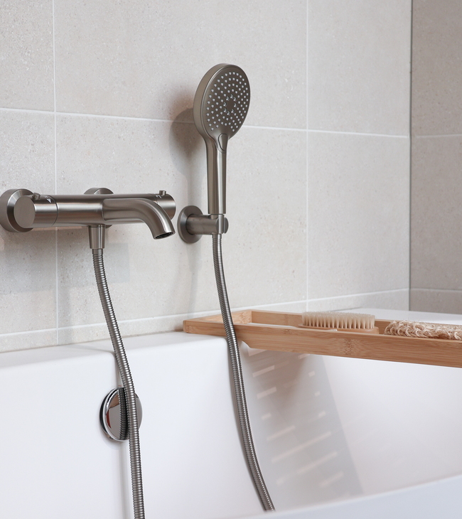Baignoire blanche en « solid surface » avec robinetterie aspect inox dans une salle de bains rénovée