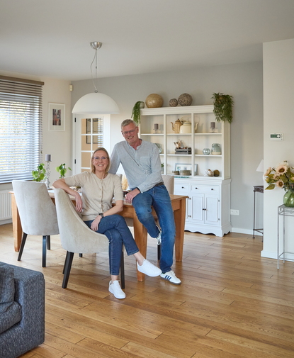 Couple satisfait posant dans leur salon après une rénovation de salle de bain réussie, au style intérieur moderne et chaleureux.