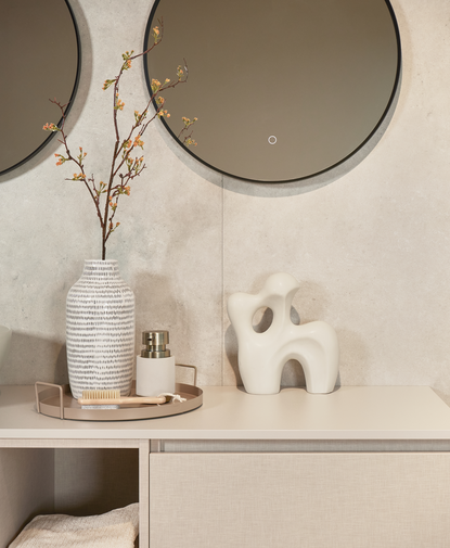 Miroir rond avec cadre noir au‑dessus d’un meuble de salle de bains moderne décoré avec accessoires